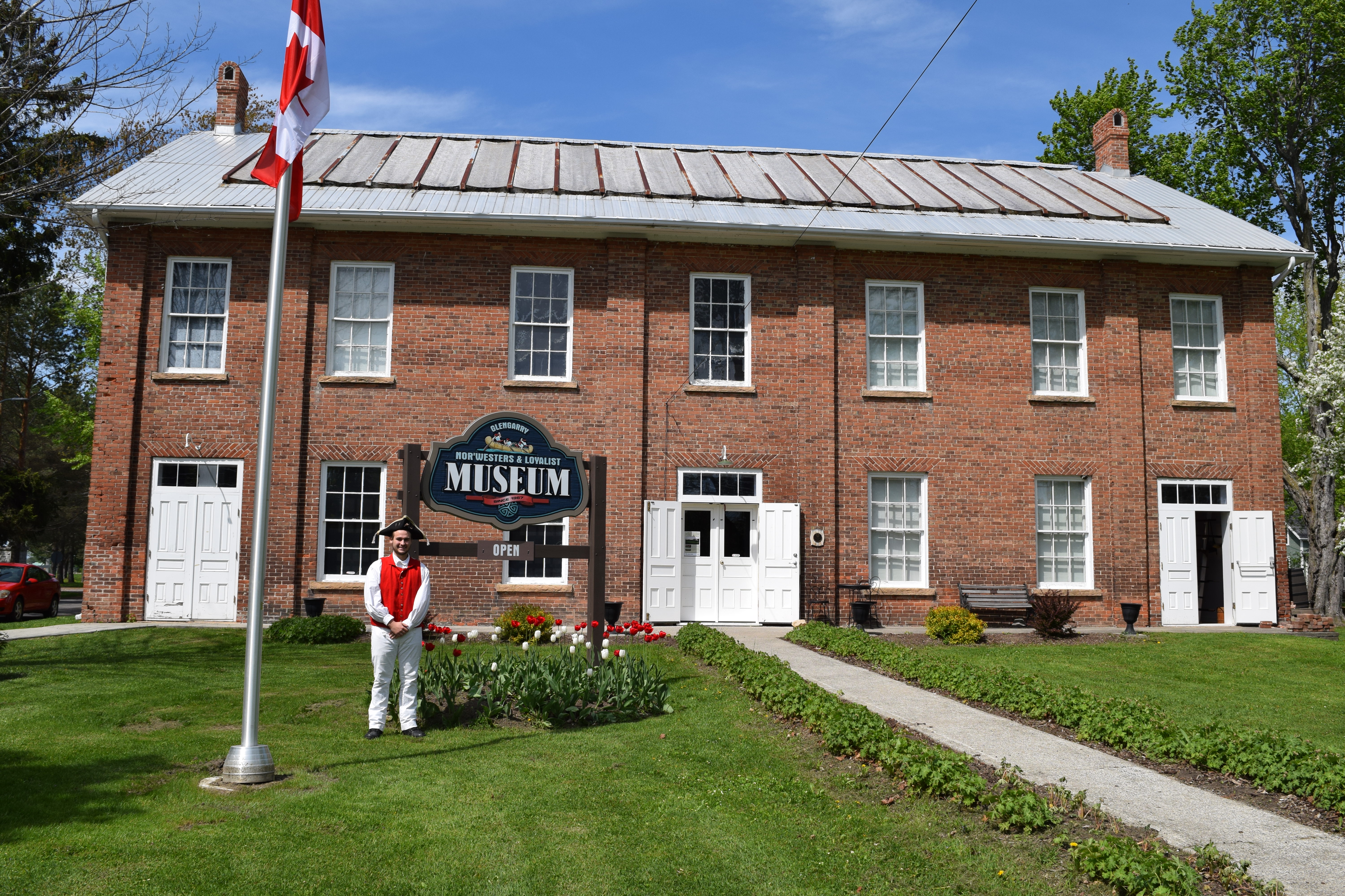 Image depicts the historic Glengarry Nor'Westers and Loyalist Museum Building with a member in uniform
