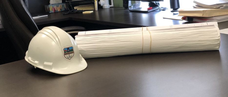 hard hat and building plans on a brown desk
